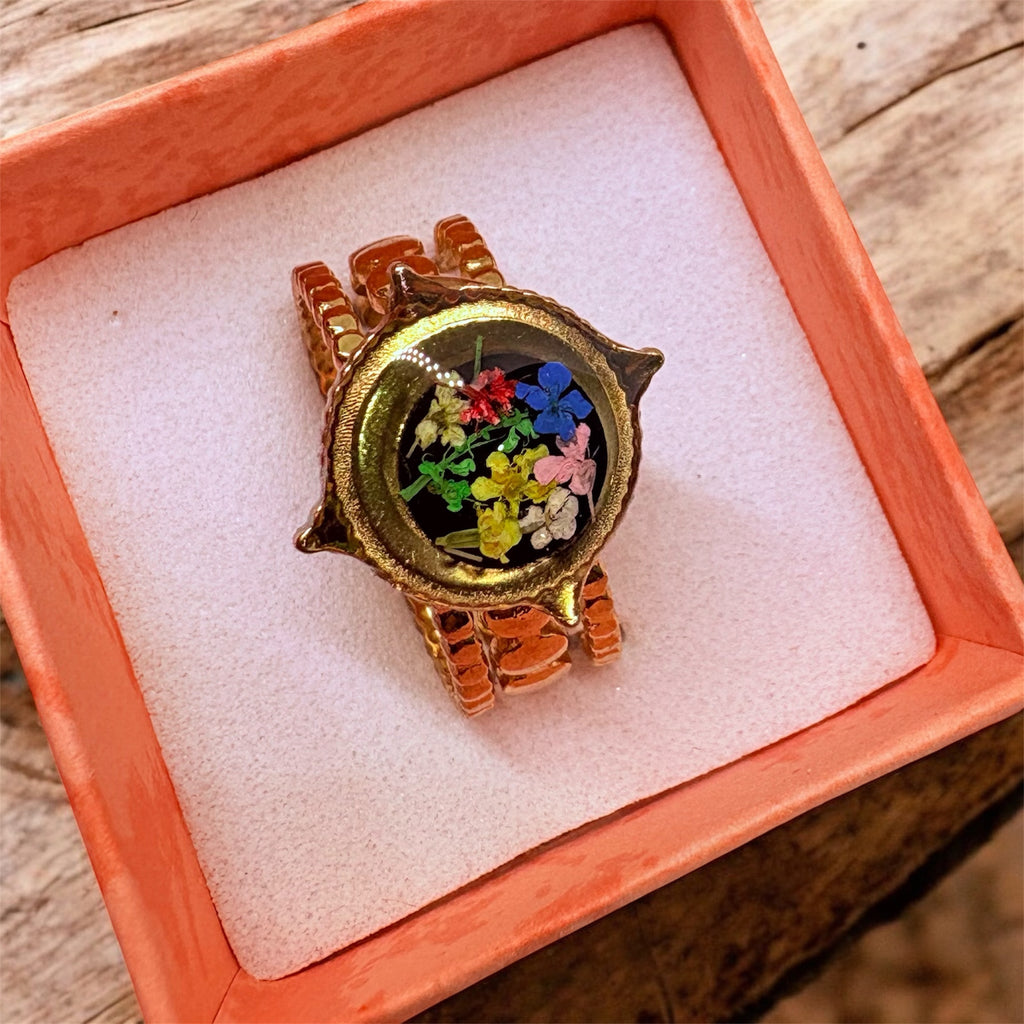 Decorative ring with colorful stones in a wooden box on a wooden surface
